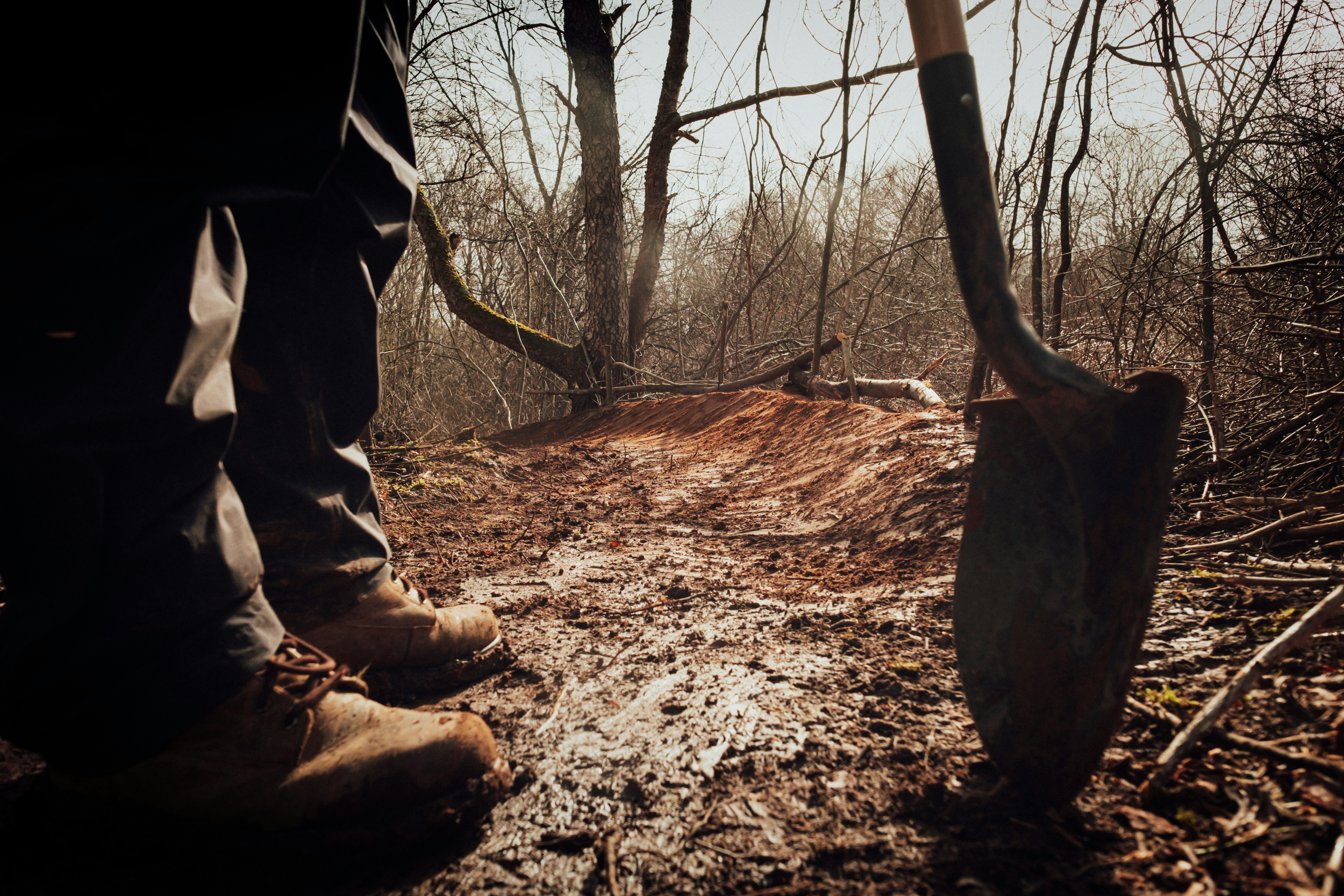 person in brown pants and brown boots holding brown wooden stick